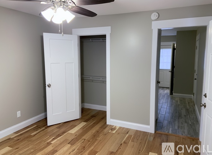 A room with a ceiling fan and a white door.
