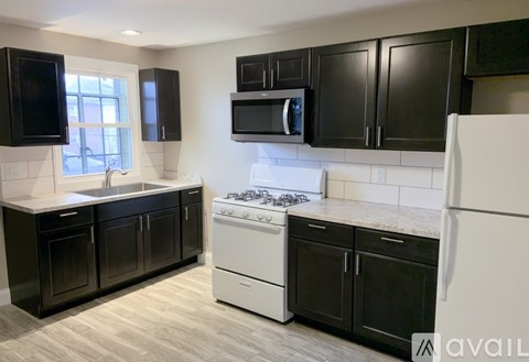 A kitchen with black cabinets and white appliances.