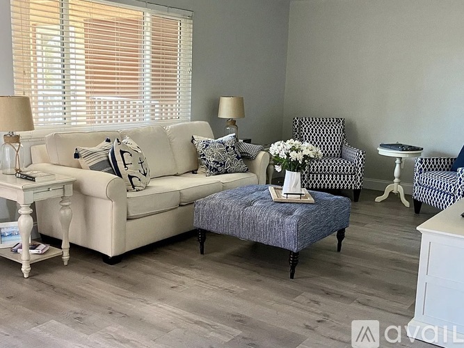 A living room with a white couch, a grey ottoman, and a matching chair.