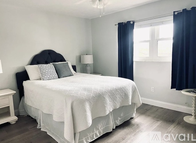 A bedroom with a large bed and a window with curtains.