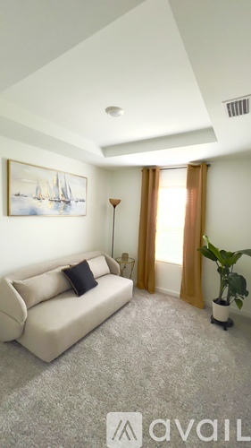 A living room with a couch, a lamp, a plant, and a painting on the wall.
