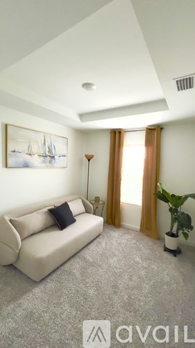 A living room with a couch, a lamp, a plant, and a painting on the wall.