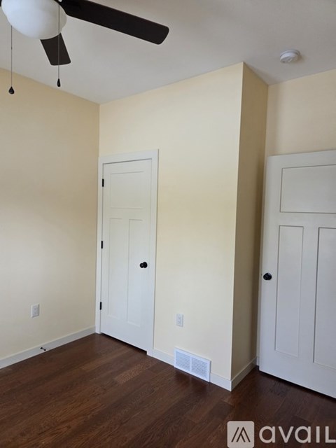 A room with a ceiling fan and two doors.