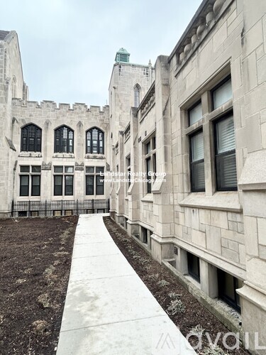 A large, grey stone building with a long white walkway in front.
