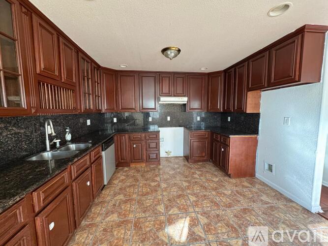 A kitchen with brown cabinets and a black countertop.
