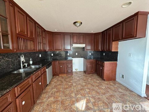 A kitchen with brown cabinets and a black countertop.