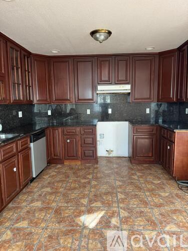 A kitchen with brown cabinets and a tiled floor.