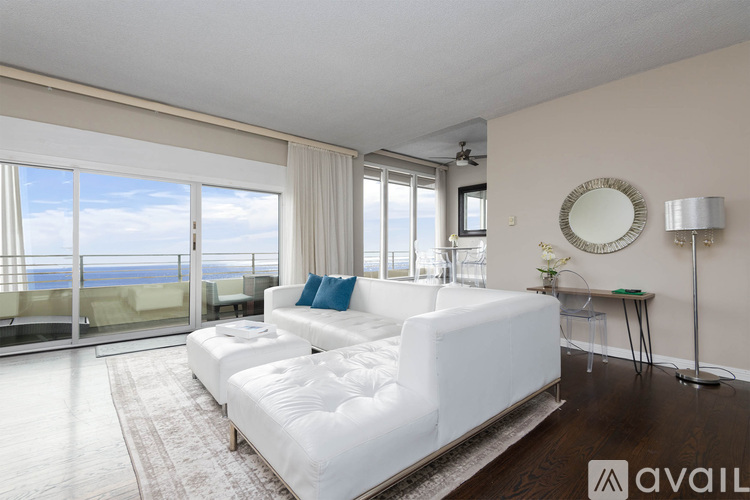 A living room with a white sofa and a round mirror on the wall.