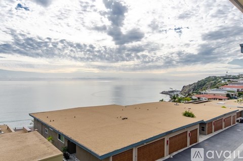 A building with a flat roof is situated on a cliff overlooking the sea.