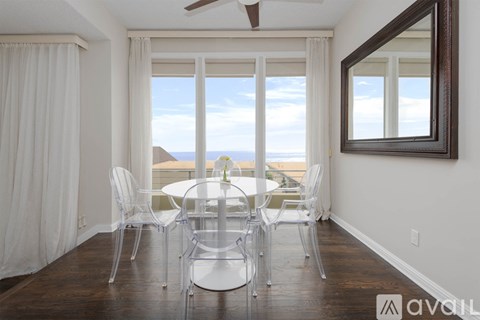 A dining room with a table and chairs and a view of the ocean.