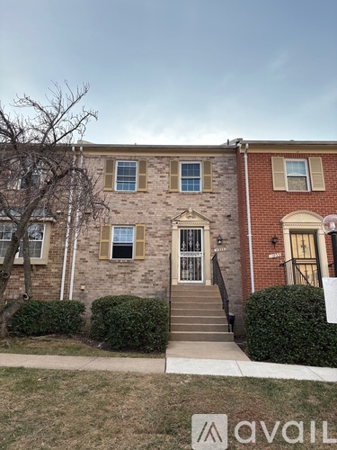 A brick house with a front yard and a tree.