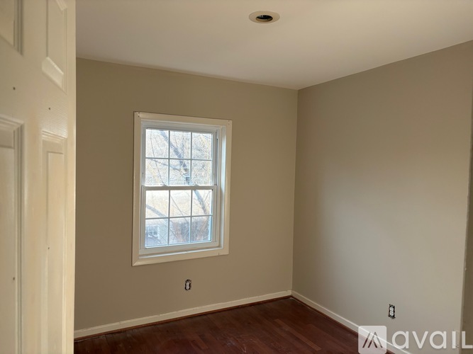 A room with a window and a wooden floor.