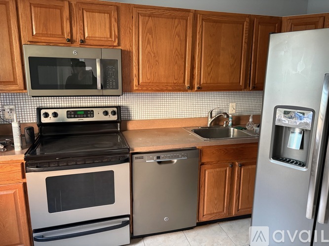 A kitchen with wooden cabinets and a stainless steel refrigerator.