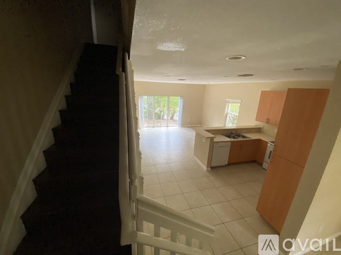 A staircase leads to a kitchen area with white cabinets and a counter.