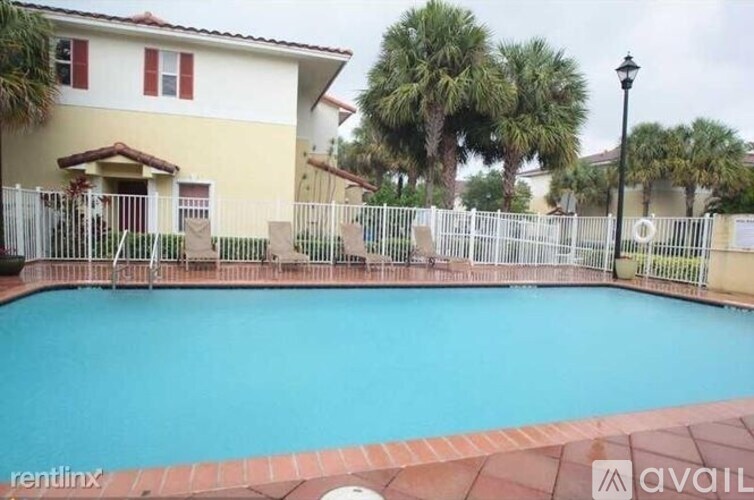 A pool in front of a house with a fence around it.