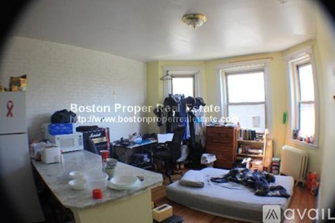 A bedroom with a bed, desk, and window.