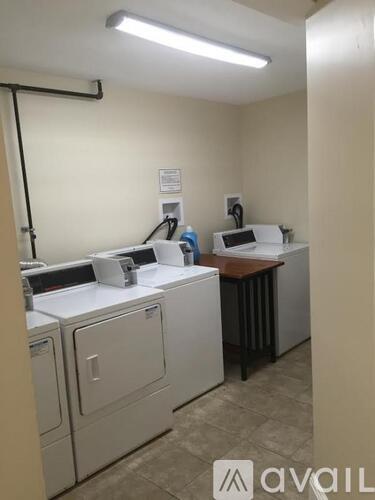 A white colored room with two white colored cabinets and a brown colored table.
