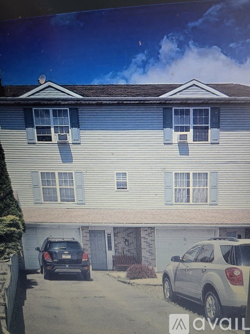 A car is parked in front of a house with a garage.