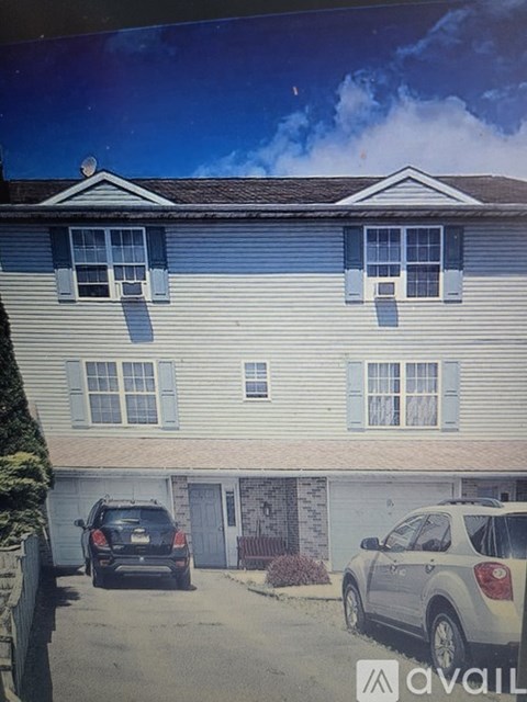 A car is parked in front of a house with a garage.