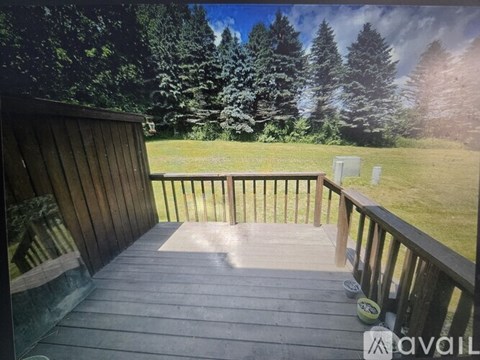 A deck with a view of a grassy field and trees.