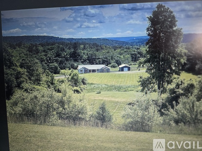 A farm with a house and a barn is surrounded by trees.