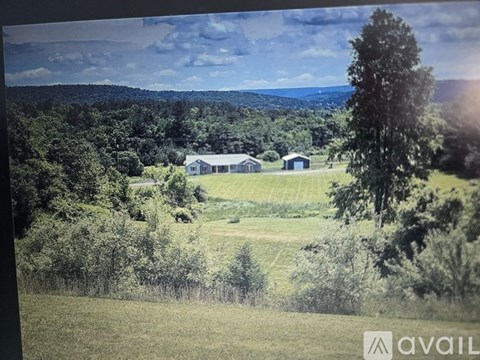 A farm with a house and a barn is surrounded by trees.