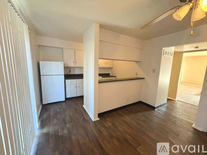 A kitchen with white appliances and wooden floors.
