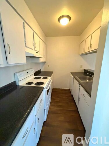 A kitchen with white cabinets and a black countertop.