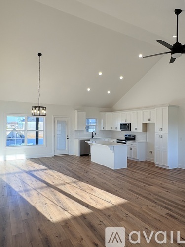 A spacious kitchen and living room with wooden floors and white walls.