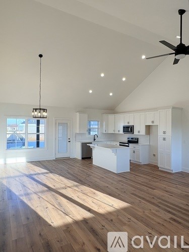 A spacious kitchen and living room with wooden floors and white walls.