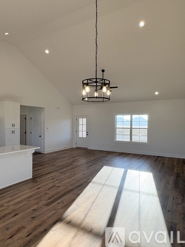 A large, empty room with wooden floors and a chandelier hanging from the ceiling.