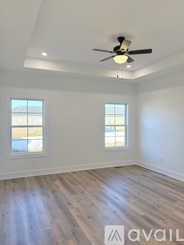 A room with a ceiling fan and two windows.