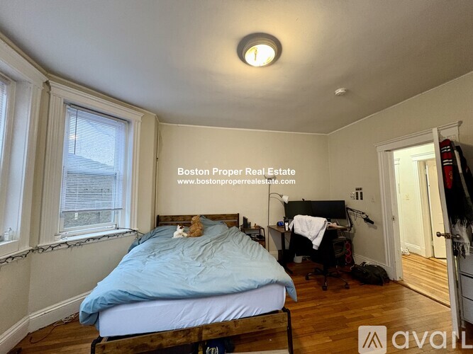 A bedroom with a bed, desk, and window.