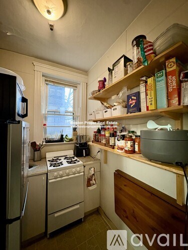 A kitchen with a stove, refrigerator, and shelves stocked with food.