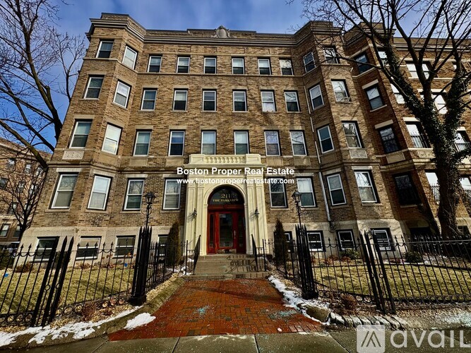 A large brown building with a red door and a sign that says Boston Proper Real Estate.