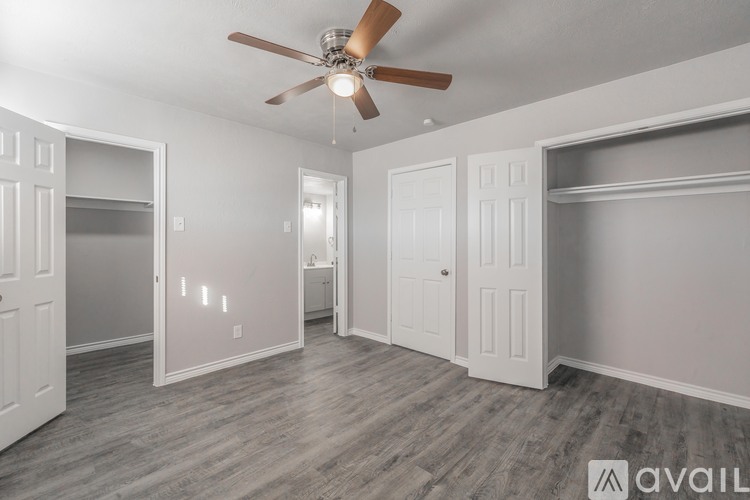 A spacious room with a ceiling fan and light fixture, and a wall-mounted shelf.