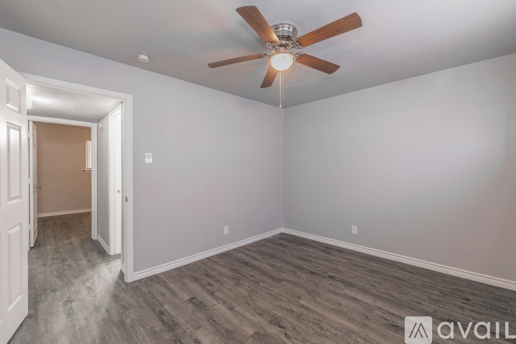 A room with a ceiling fan and light fixture, and a doorway leading to another room.