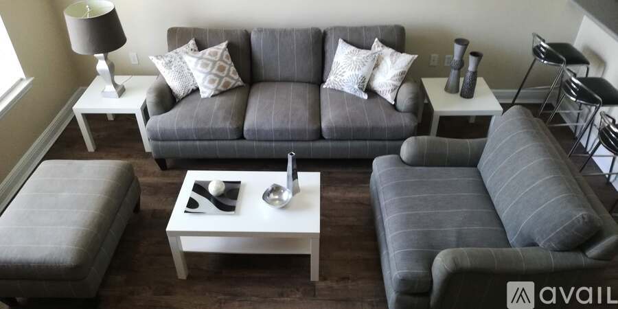 A living room with a grey couch, a white coffee table, and a grey ottoman.