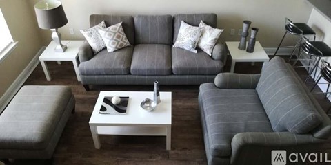 A living room with a grey couch, a white coffee table, and a grey ottoman.