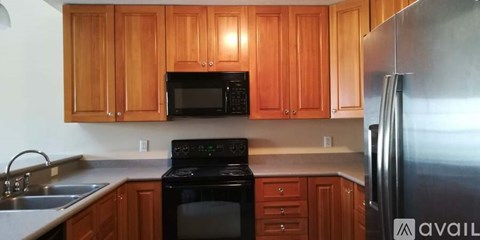 A kitchen with wooden cabinets and a stainless steel refrigerator.