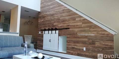 A living room with a grey couch and a wooden wall.