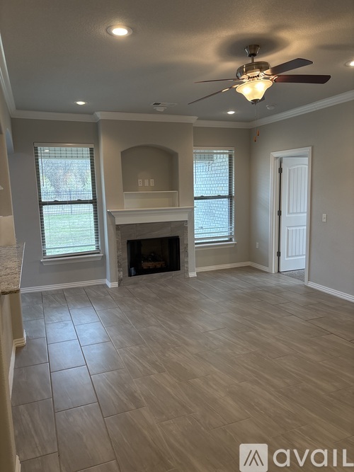 A spacious room with a fireplace and a ceiling fan.