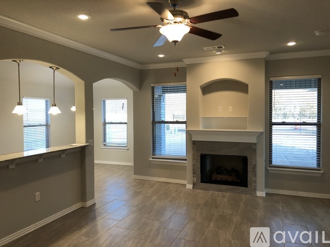 A spacious living room with a fireplace and a ceiling fan.