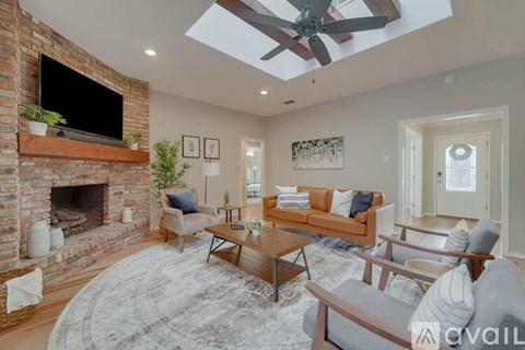 A living room with a brick fireplace and a ceiling fan.