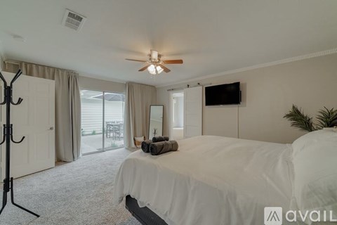 A bedroom with a large bed and a ceiling fan.