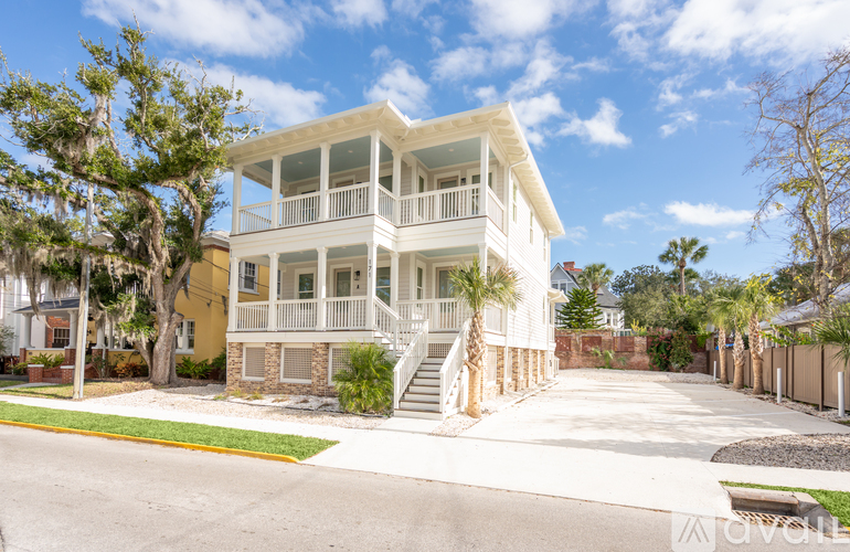 A two-story house with a white exterior and a balcony on the second floor.