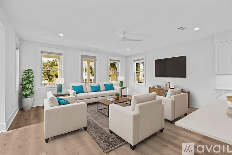 A living room with white furniture and a flat screen TV mounted on the wall.