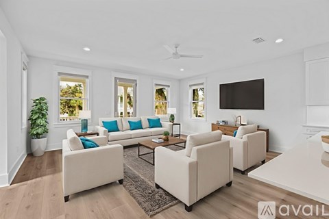 A living room with white furniture and a flat screen TV mounted on the wall.