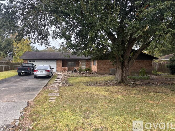 A house with a tree in front and a car parked in the driveway.
