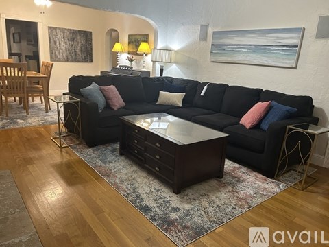 A living room with a black couch and a coffee table.